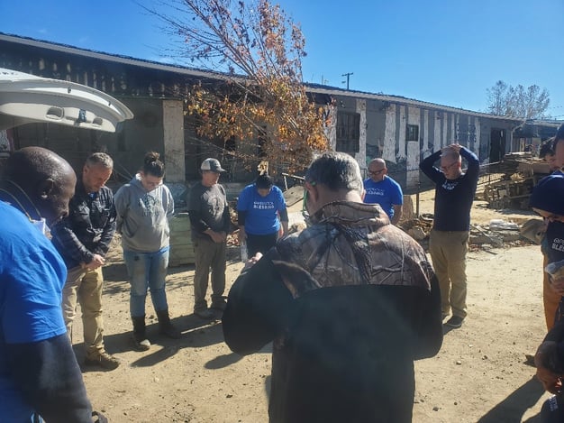 team members standing in a circle praying