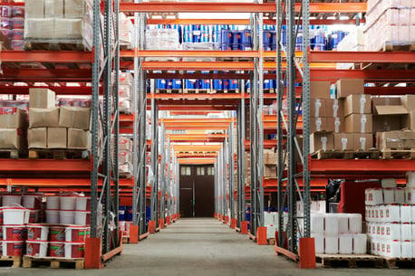 a neatly organized warehouse, products stacked neatly on pallets that are on shelves