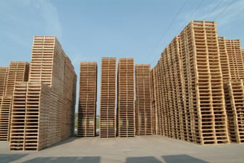 several tall stacks of pallets on concrete outdoors